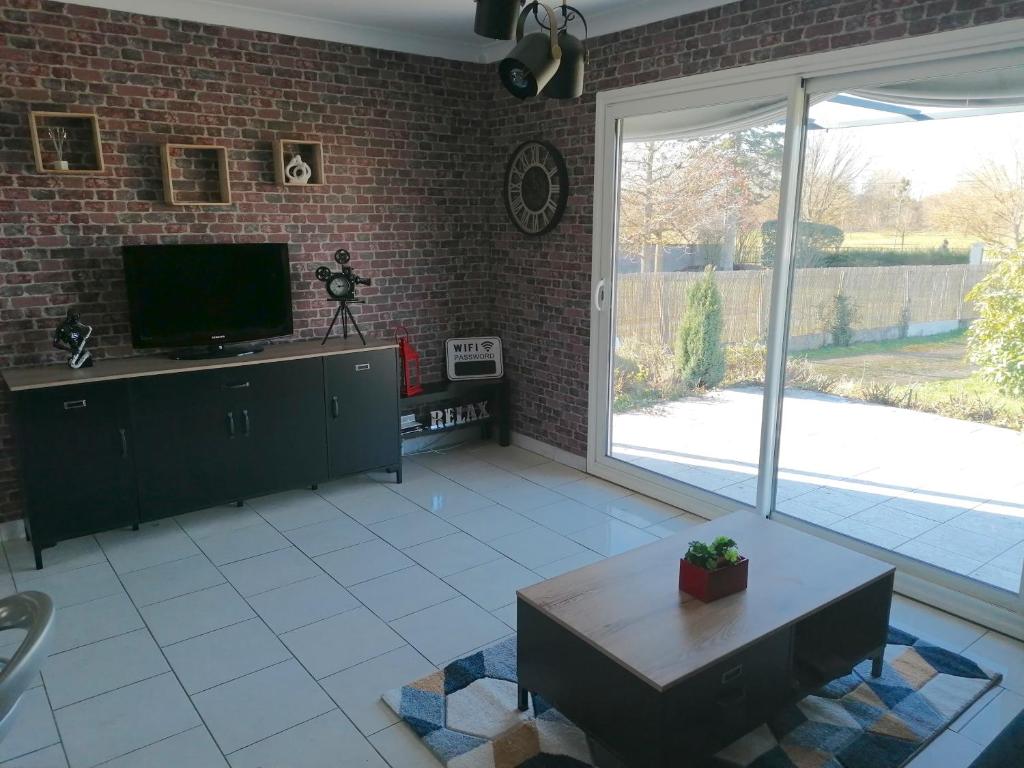 sala de estar con TV y pared de ladrillo en Gîte Au fil de l'eau, en Muides-sur-Loire