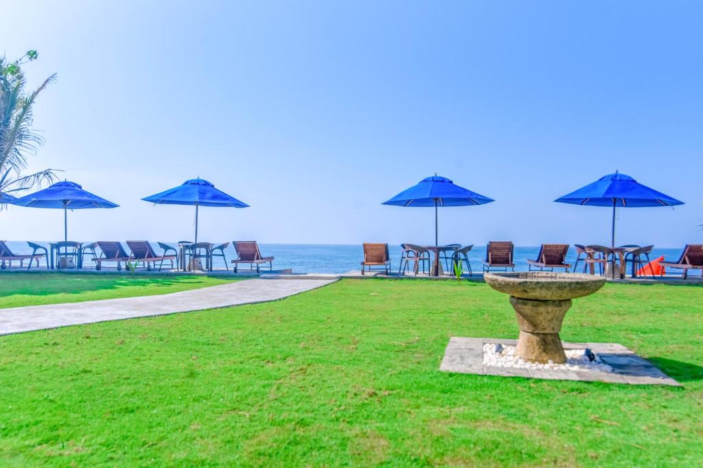 a bird bath with chairs and umbrellas on the beach at Amanda Beach Villas in Unawatuna