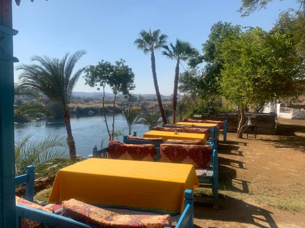 a row of tables and chairs next to a river at Nubian Farm Aswan in Aswan