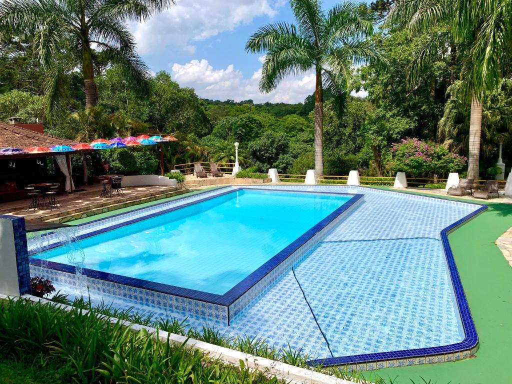 uma grande piscina com azulejos azuis no chão em Pousada Serra das Araucárias em São Roque
