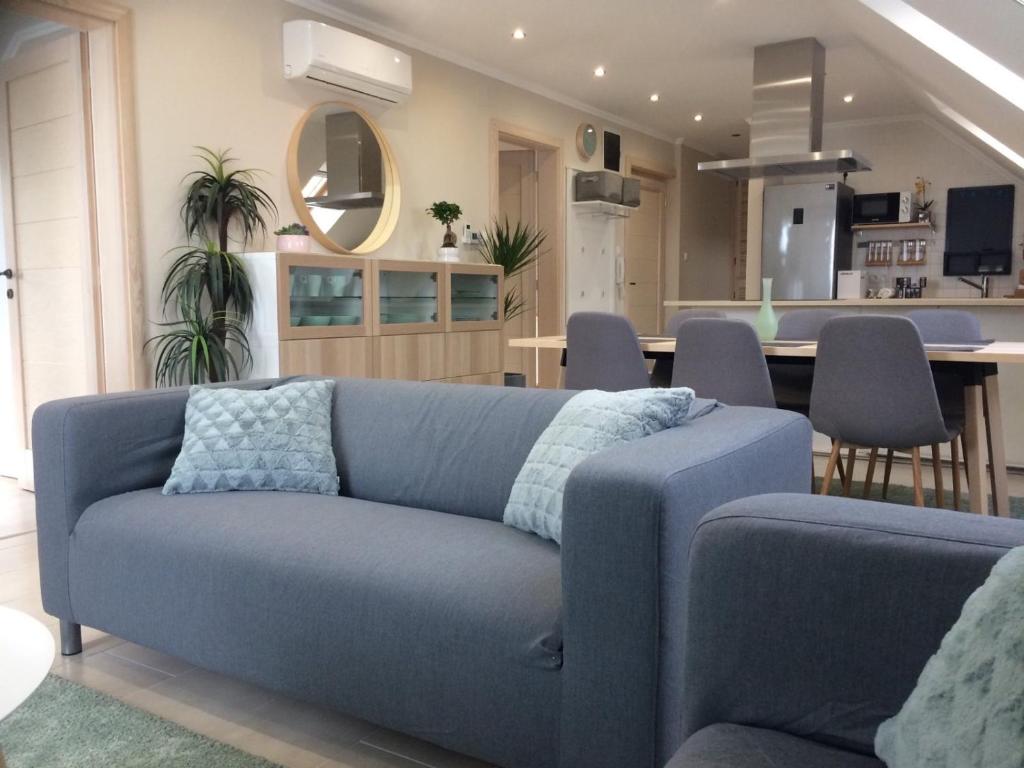 salon z niebieską kanapą i jadalnią w obiekcie Galéria Apartmanház w mieście Keszthely