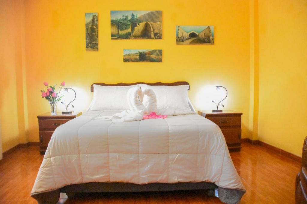 a bedroom with a white bed with two tables and two lamps at Hospedaje Claudia in Ica