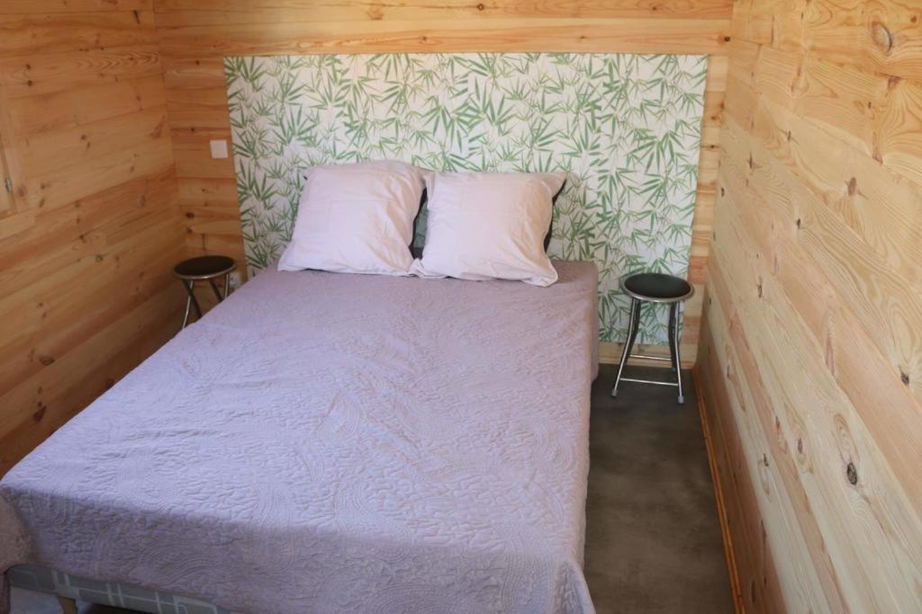 a bed in a wooden room with two pillows at Grand Chalet Domaine du vieux chêne in Bergerac