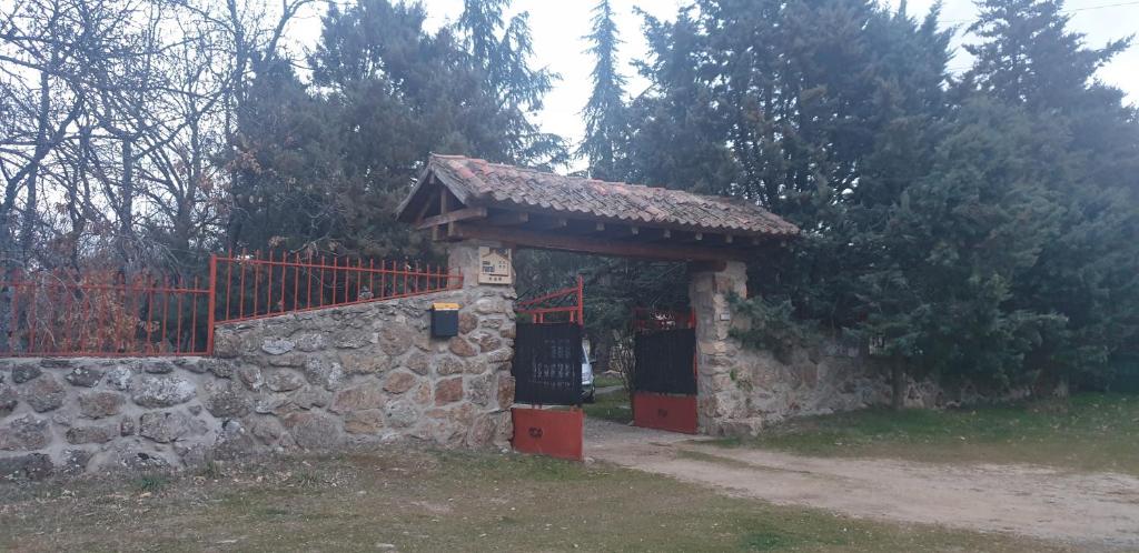 un bâtiment en pierre avec un portail et une clôture dans l'établissement Exclusiva Casa y Finca Privada ITOS, à Pelayos del Arroyo