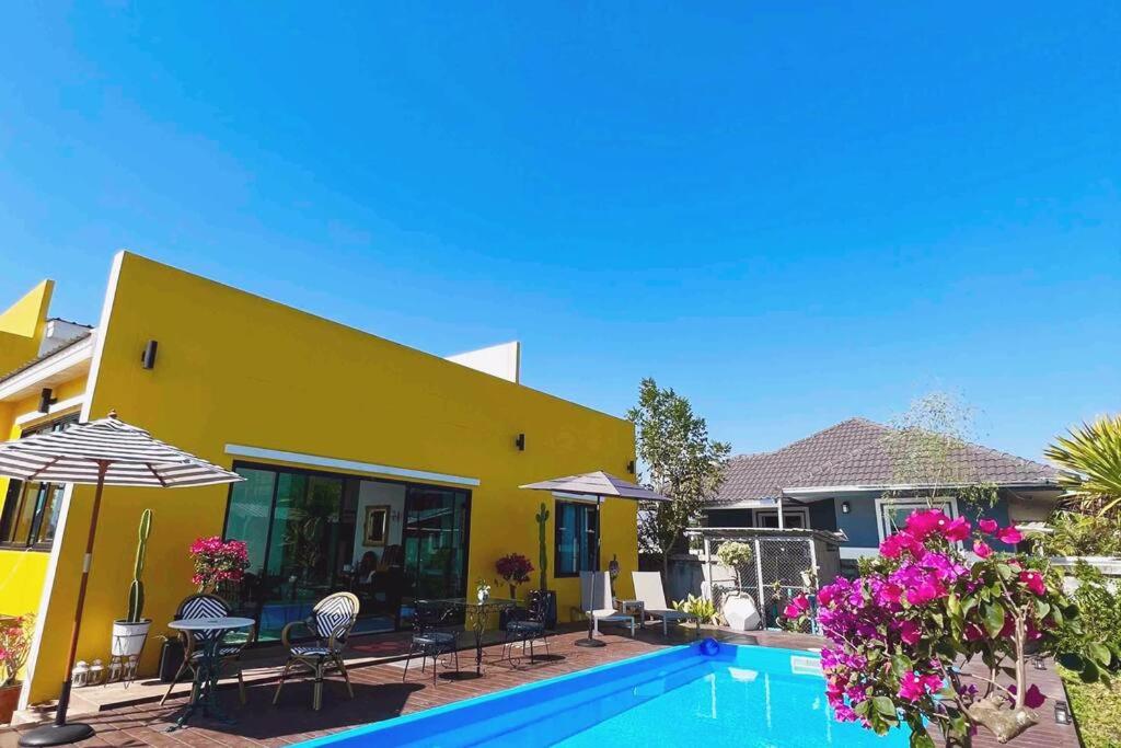 a yellow house with a swimming pool in front of it at Colorful Pool Villa, Chiang Rai, Thailand in Chiang Rai