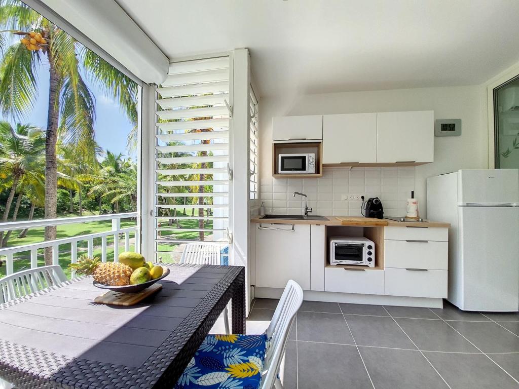 uma cozinha com uma mesa com uma tigela de frutas sobre ela em Studio CocoCaraïbes Anse des Rochers vue mer - piscine em Belle-Allée