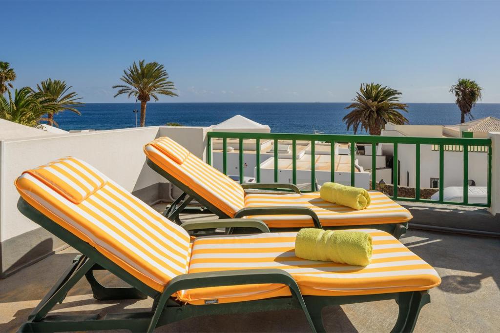 twee ligstoelen op een balkon met de oceaan op de achtergrond bij Lanzahost Villa Ona in Costa Teguise
