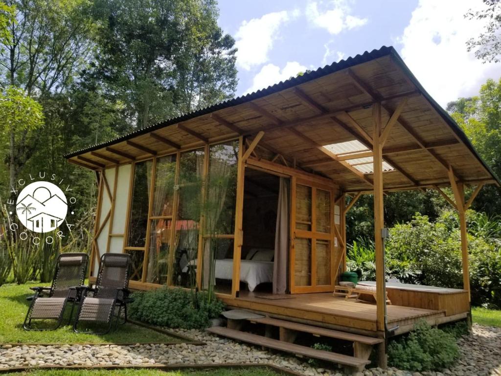 un pabellón de madera en un jardín con 2 sillas en Exclusivo Cocora con Jacuzzi Salento Quindio, en Salento