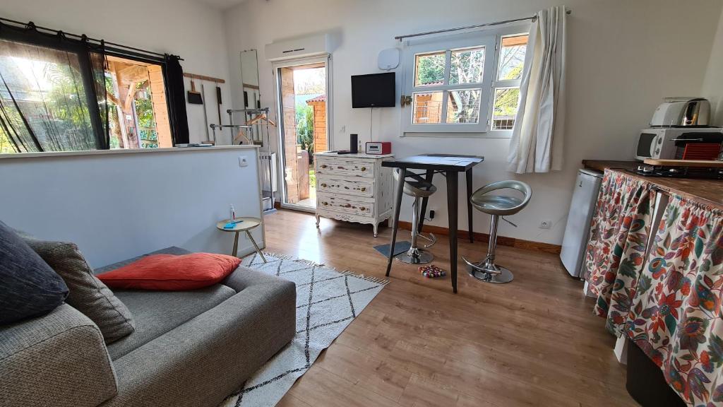 a living room with a couch and a desk and window at Charmant logement avec parking in Orvault