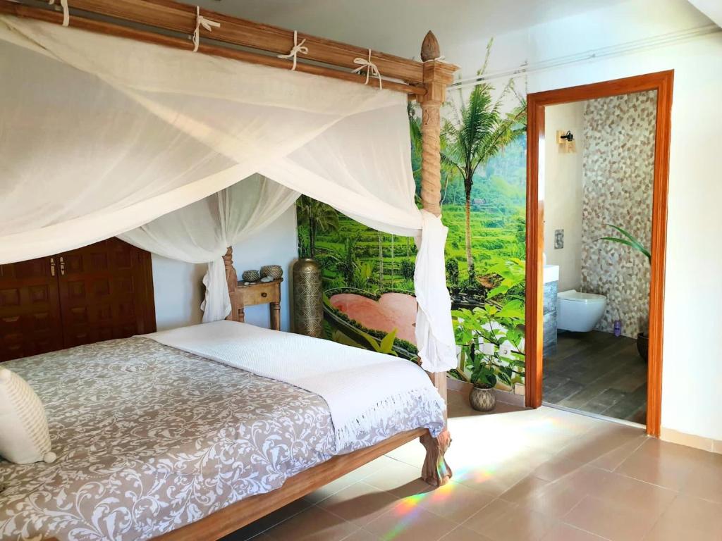 a bedroom with a canopy bed and a bathroom at Little Bali Javea in Jávea