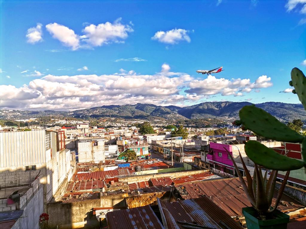 um avião está a sobrevoar uma cidade com edifícios em Life Builders em Guatemala