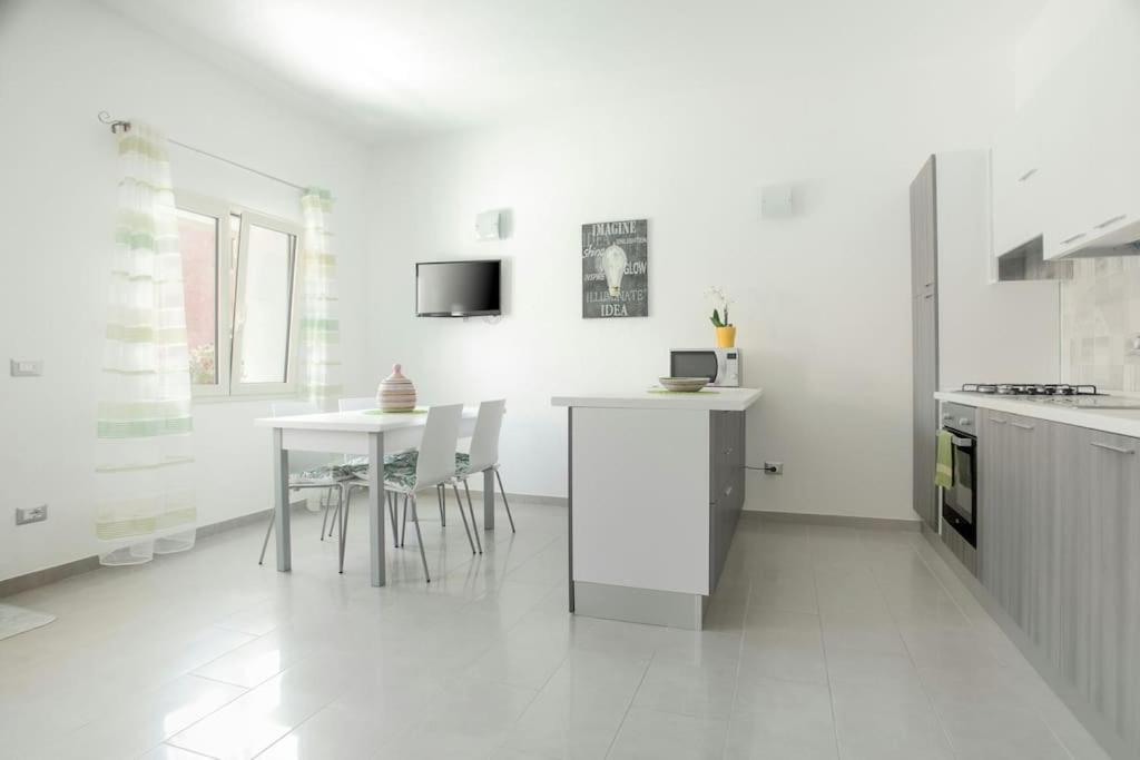 a white kitchen with a table and chairs in it at Nuovo trilocale vicino centro/mare in Santa Teresa Gallura