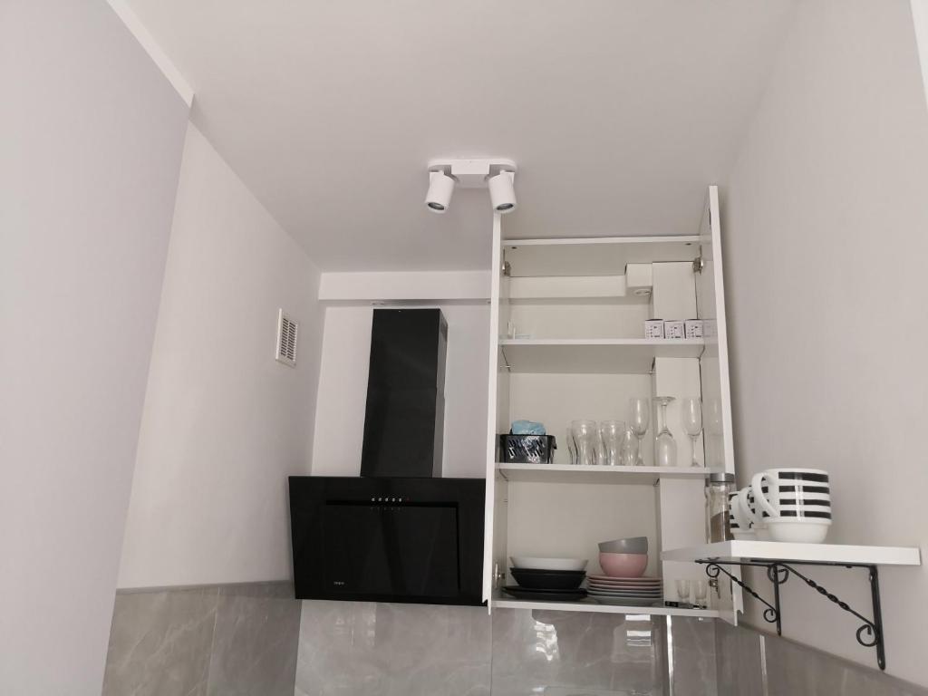 um quarto com paredes brancas, um armário preto e prateleiras em Różowe sny em Klodzko