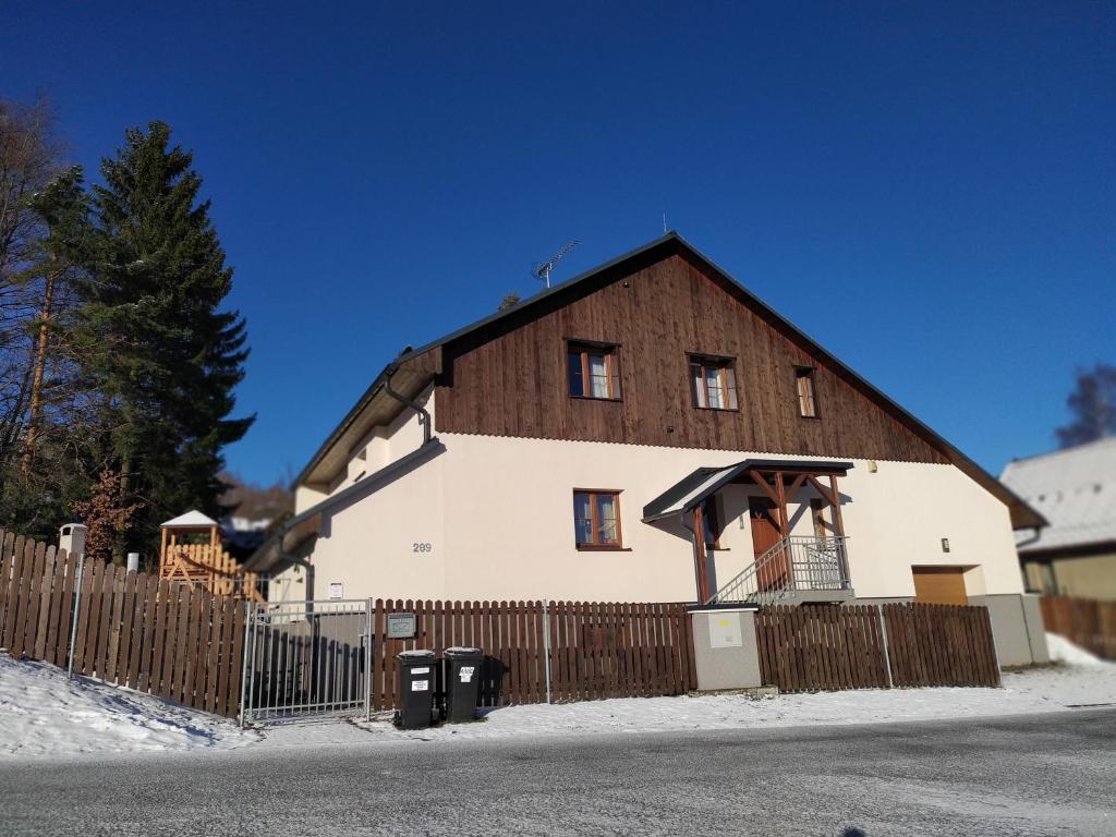 ein großes weißes Haus mit einem Holzzaun in der Unterkunft Haus Tolštejn in Jiřetín pod Jedlovou