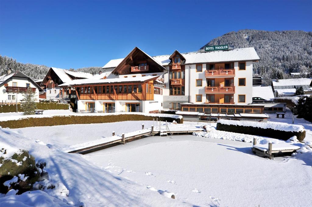 un grande edificio nella neve di fronte di Hotel Naggler Weissbriach a Weissbriach
