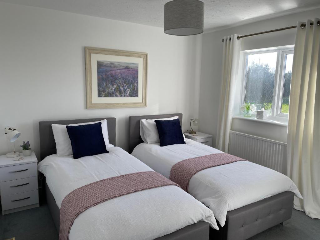 two beds sitting next to each other in a bedroom at Comfortable and Spacious Superb Holiday Home in Llanelli, Dog Friendly in Llanelli