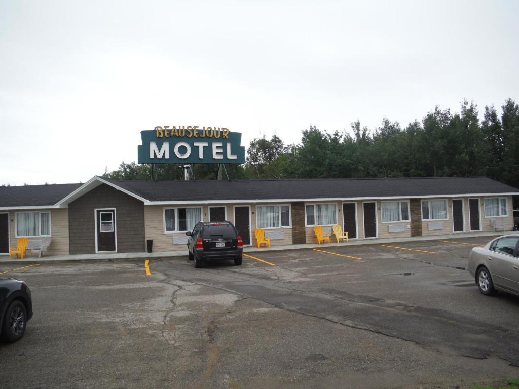 un motel con coches aparcados en un estacionamiento en Motel Beausejour, en Neguac