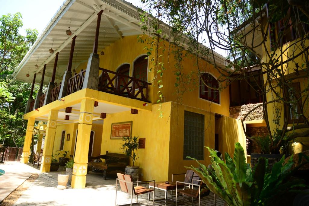 a yellow building with tables and chairs in front of it at Thambapanni Retreat in Unawatuna