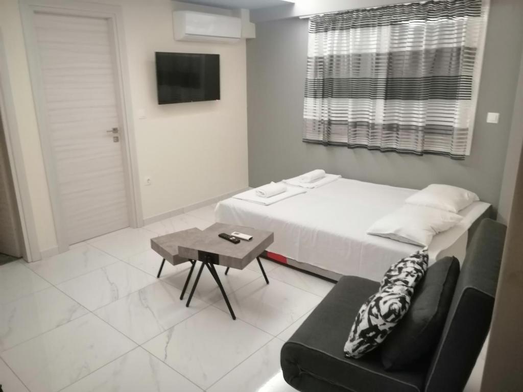 a bedroom with a bed and a couch and a table at Premium apartman Family in Paralia Katerinis