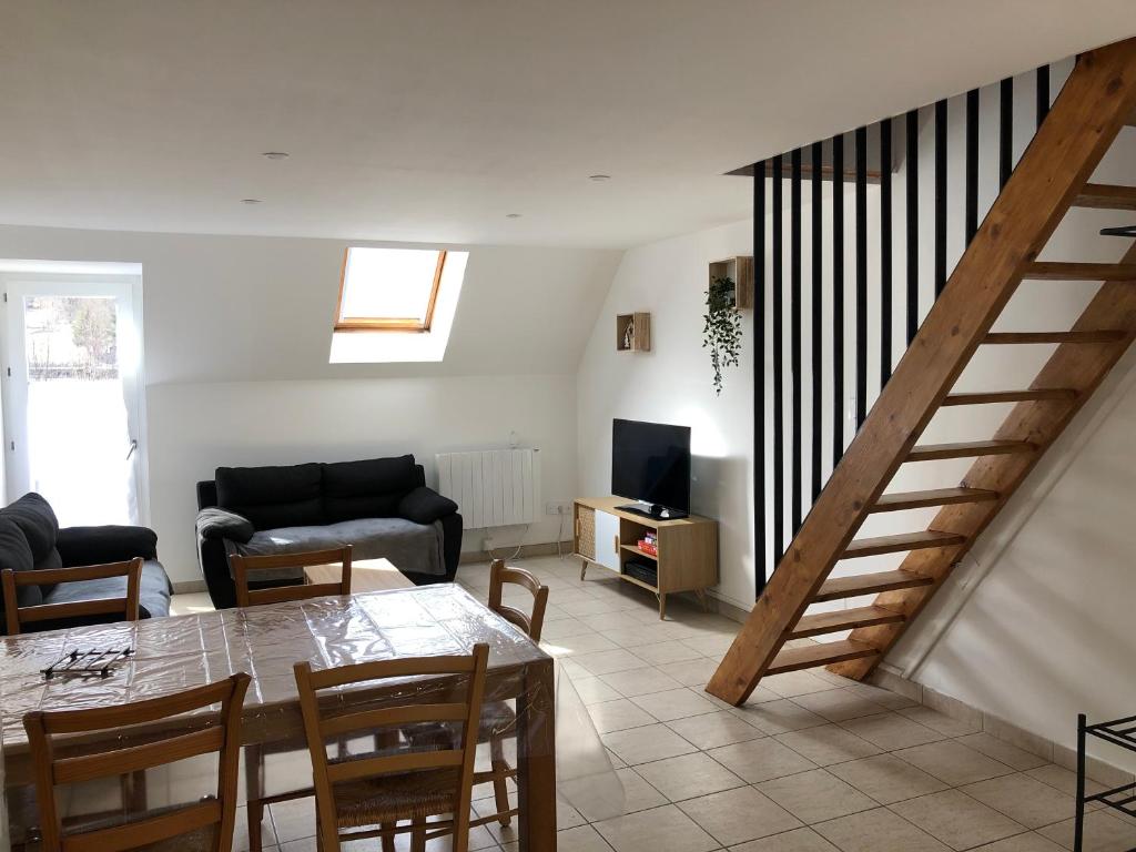 a living room with a dining room table and a staircase at Les Badalans in Loudenvielle