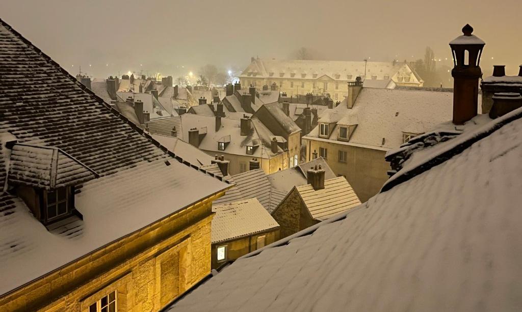 une ville recouverte de neige avec des toits et des bâtiments dans l'établissement BELLEVUE Appartement sous les toits hypercentre climatisé, à Dole