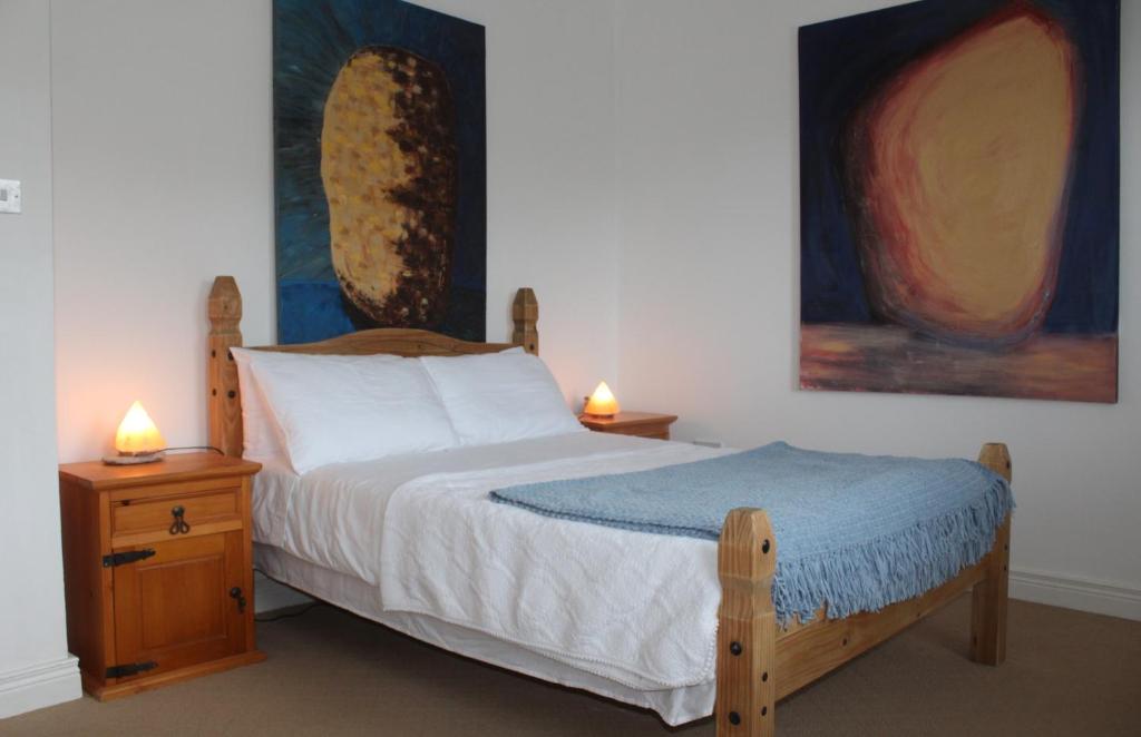 ein Schlafzimmer mit einem Holzbett mit zwei Nachttischen und zwei Lampen in der Unterkunft Malin Head SolasTobann ArtHouse Room 1 En-suite in Malin Head