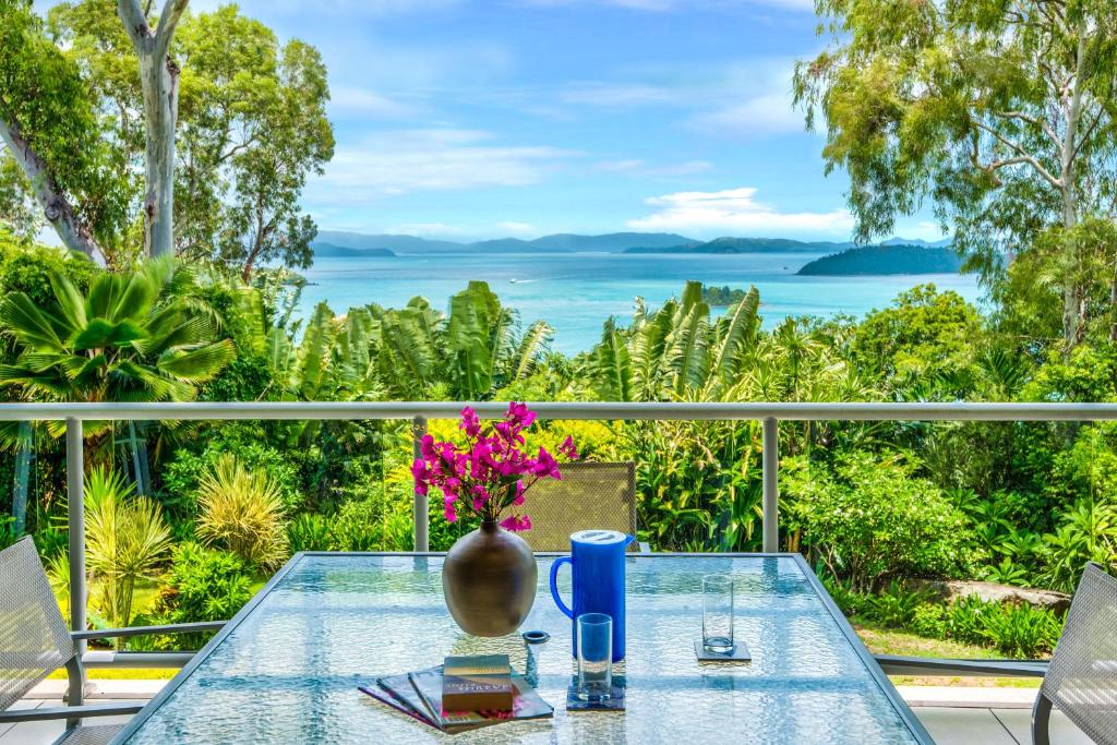 una mesa de cristal con un jarrón de flores en el balcón en Blue Water Views Apartments, en Hamilton Island