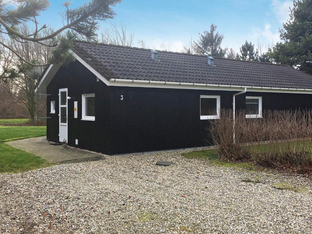 OksbølにあるThree-Bedroom Holiday home in Oksbøl 13の白い扉と砂利の私道のある黒い家