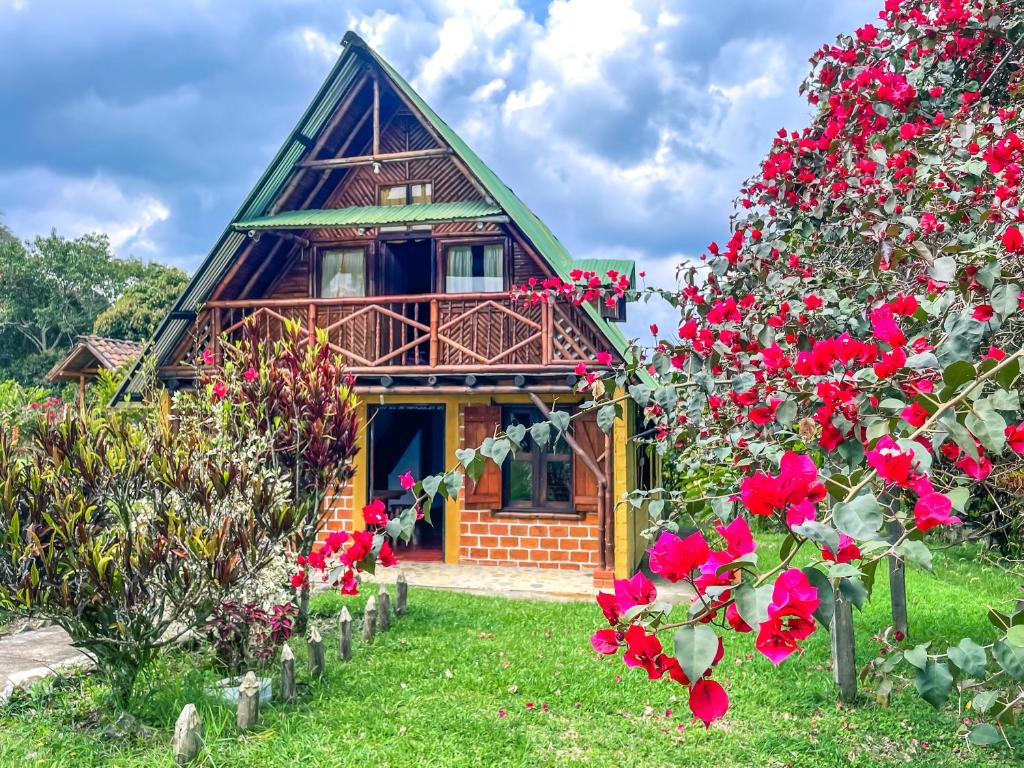 a house with red roses in front of it at Cabaña Numbana San Agustín in San Agustín