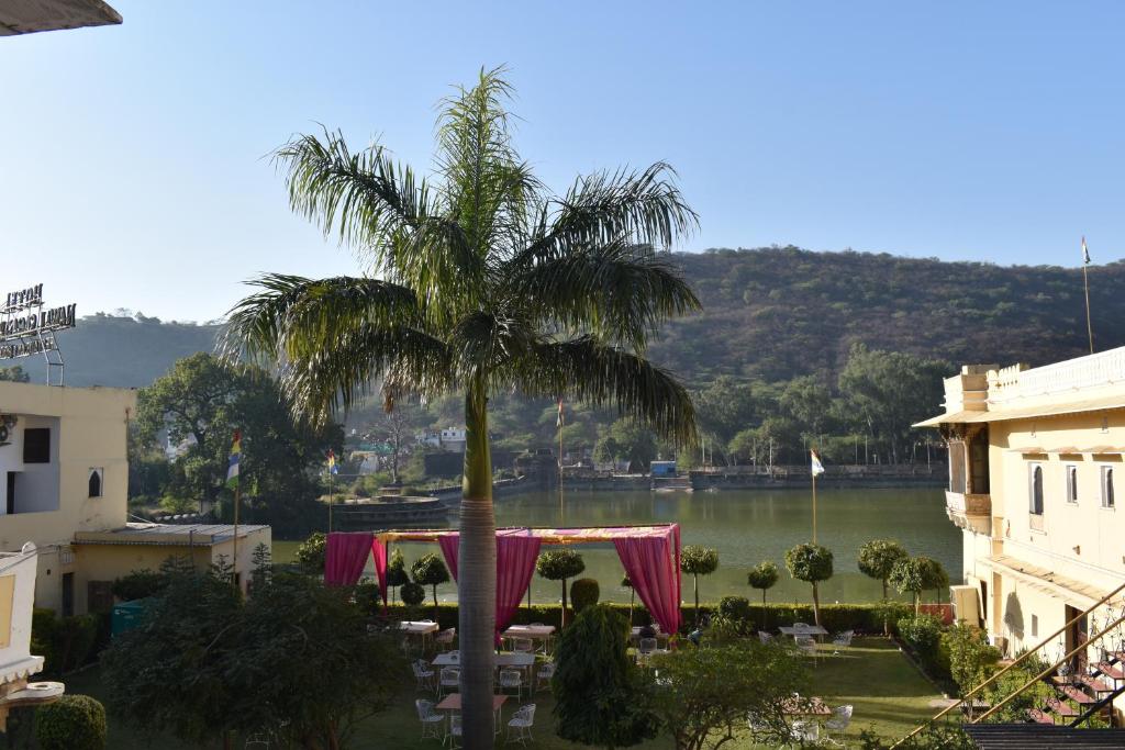 a palm tree with a table in front of a lake at Hotel Nawal Sagar Palace - Bundi in Būndi