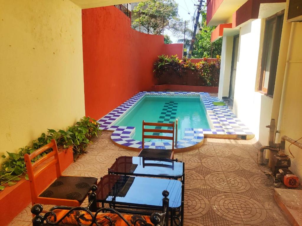 Hilltop 4 BHK Villa with Private Swimming Pool near Candolim في أولد غوا: مسبح مع كرسيين بجانب مبنى