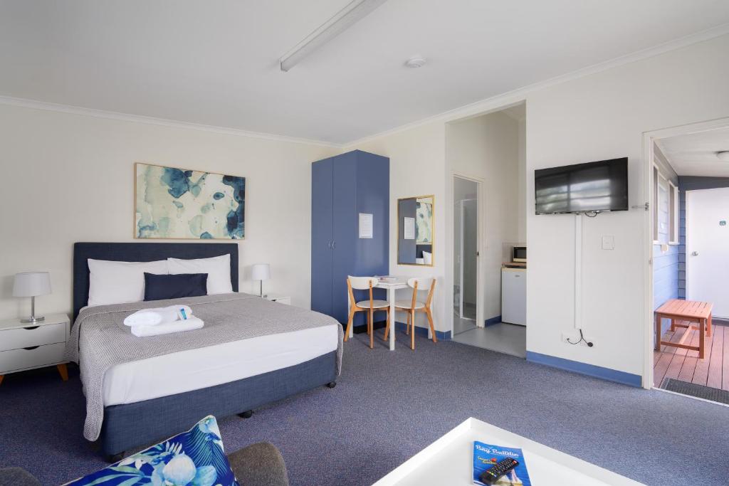 a hotel room with a bed and a table and chairs at Tin Can Bay's Sleepy Lagoon Motel in Tin Can Bay