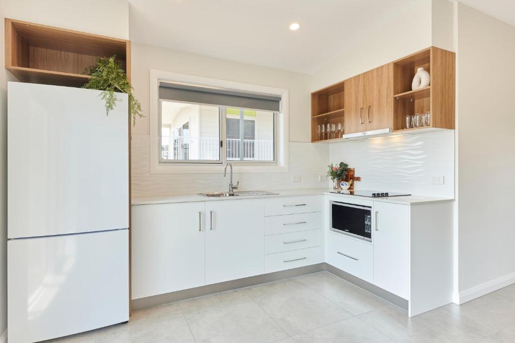 a kitchen with white cabinets and white appliances at BIG4 Launceston Holiday Park in Launceston