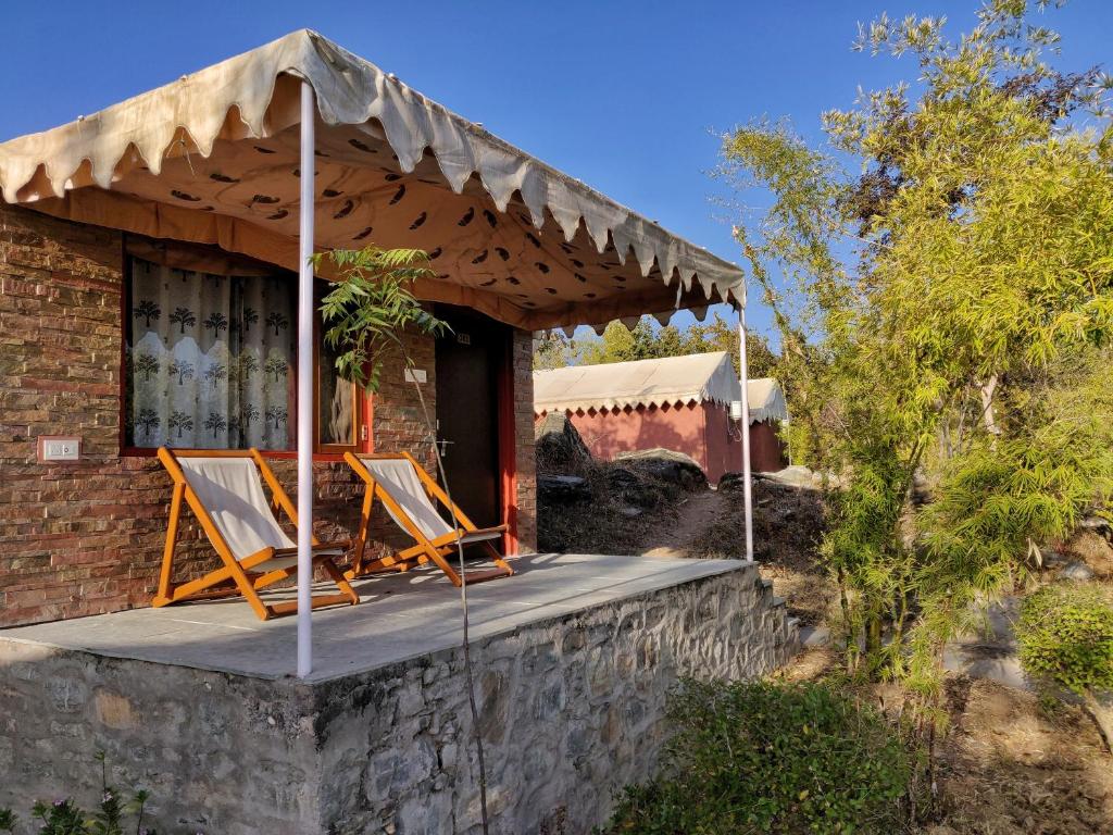 una casa con un porche con sillas. en The Sky Imperial Jungle Camp Resort, en Kumbhalgarh