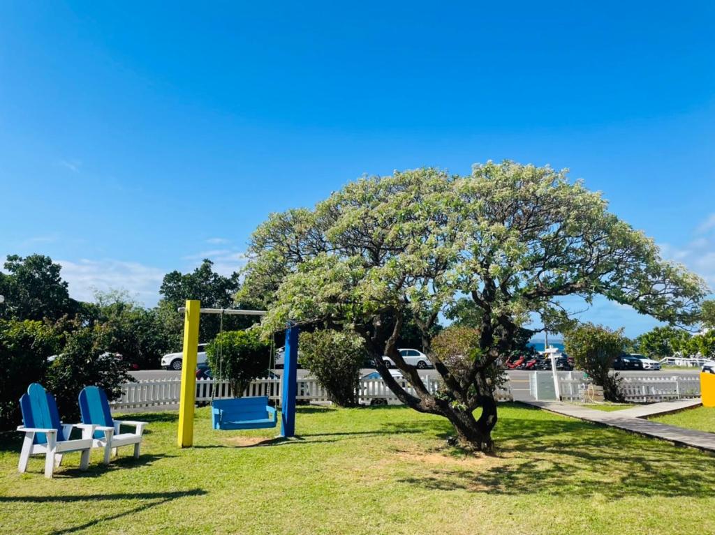 a park with blue and white chairs and a tree at Canaan B&amp;B Kenting in Eluan