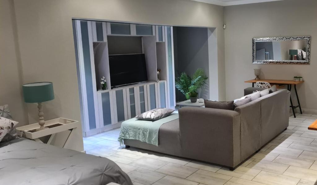 Una sala de estar con un sofá, una cama y un televisor. en Bayswater Guest Rooms, en Bloemfontein
