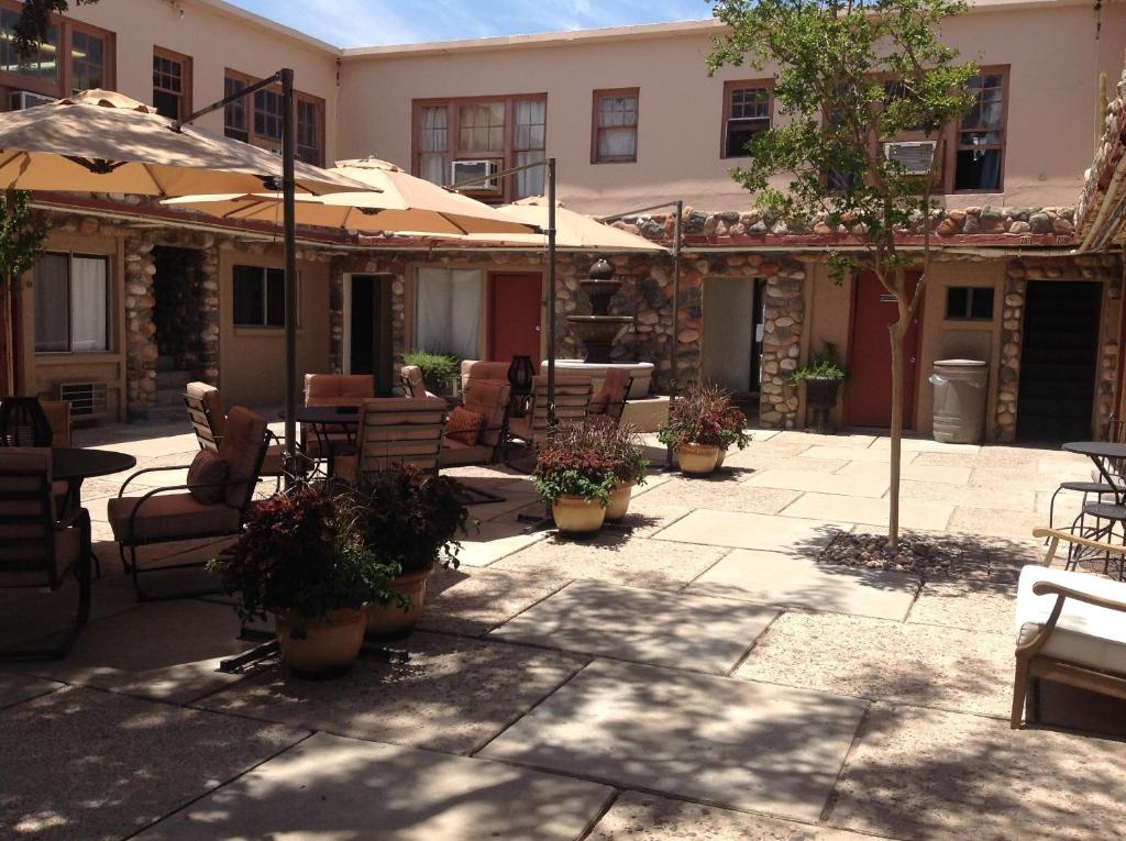 un patio al aire libre con sillas, mesas y sombrillas en Iron Horse Inn, en Cottonwood