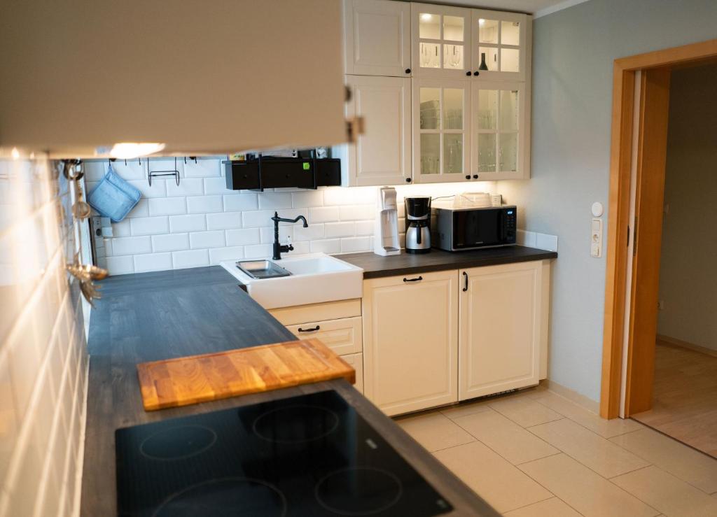 cocina con armarios blancos y encimera negra en Elbtal-Apartment en Heidenau