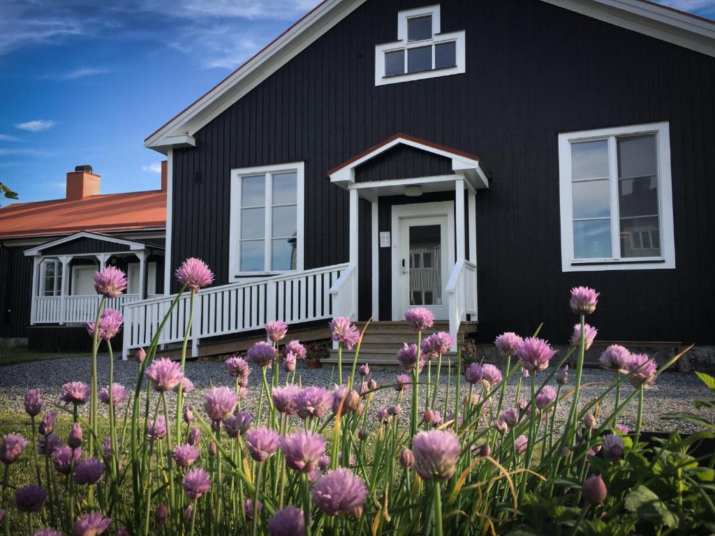 een zwart huis met roze bloemen ervoor bij Stilleben Hotell in Åmot