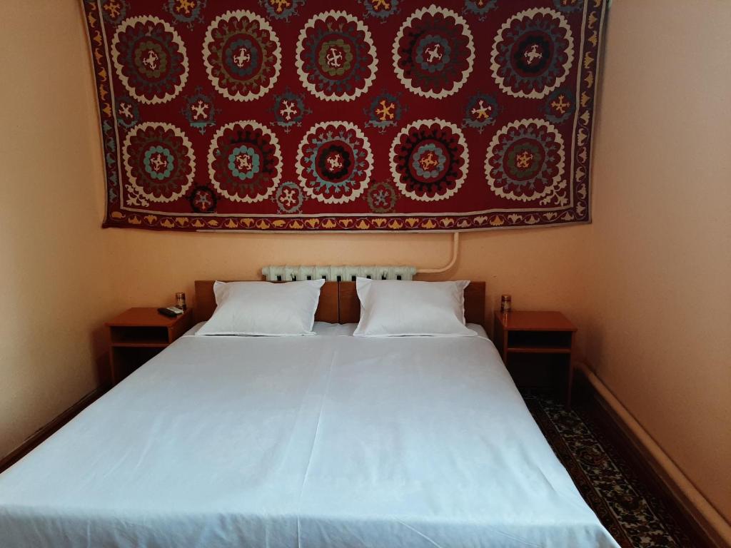 ヒヴァにあるRoyal Khiva Hotelの壁画が飾られた部屋のベッド1台