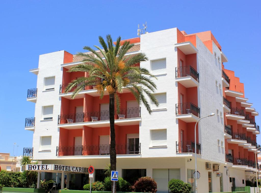 a building with a palm tree in front of it at Hotel Caribe in Rota