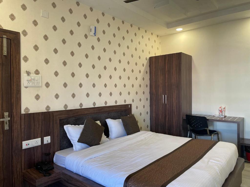a bedroom with a large bed and a wall at Hotel Royal Embassy in Tinsukia