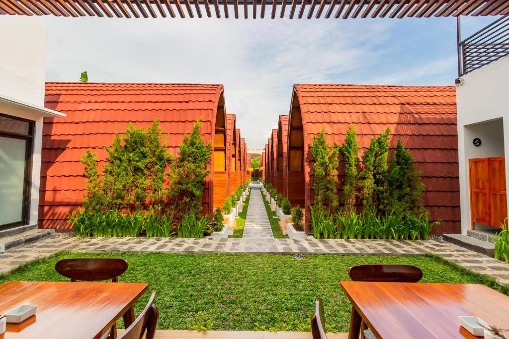 Omah Lumbung Yogyakarta في Seturan: حديقة ذات سطوح حمراء وطاولات خشبية