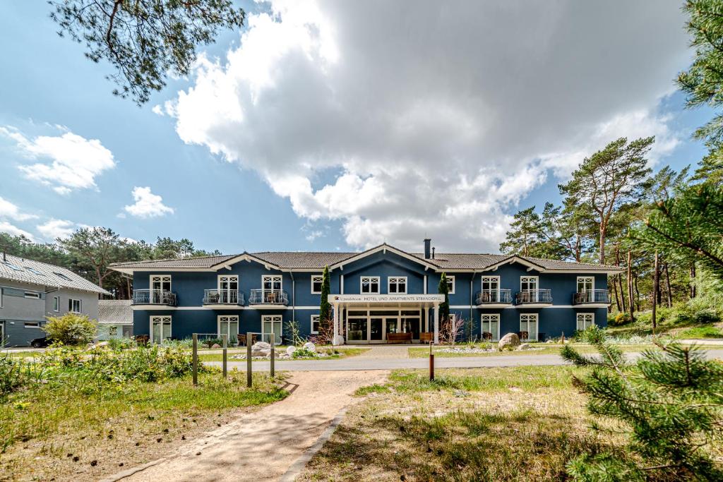 a large blue house with a driveway at Upstalsboom Hotel Strandidyll in Trassenheide