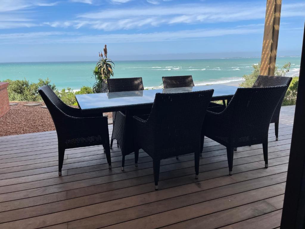 a table and chairs on a deck with the beach at 4 Zwaan in Jeffreys Bay