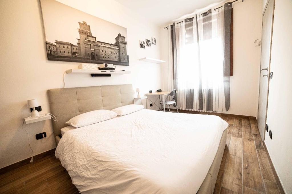 um quarto com uma cama branca e uma janela em La dolce vita em Ferrara