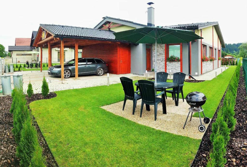 a grill and a table and chairs in a yard at Apartmany Butterfly in Bešeňová