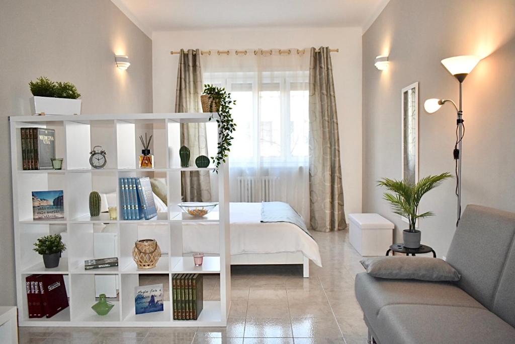 uma sala de estar com uma cama e uma estante de livros brancos em CASA BRAMANTE Stile e Comodità tra Inalpi Arena e il Cuore della Città! em Turim