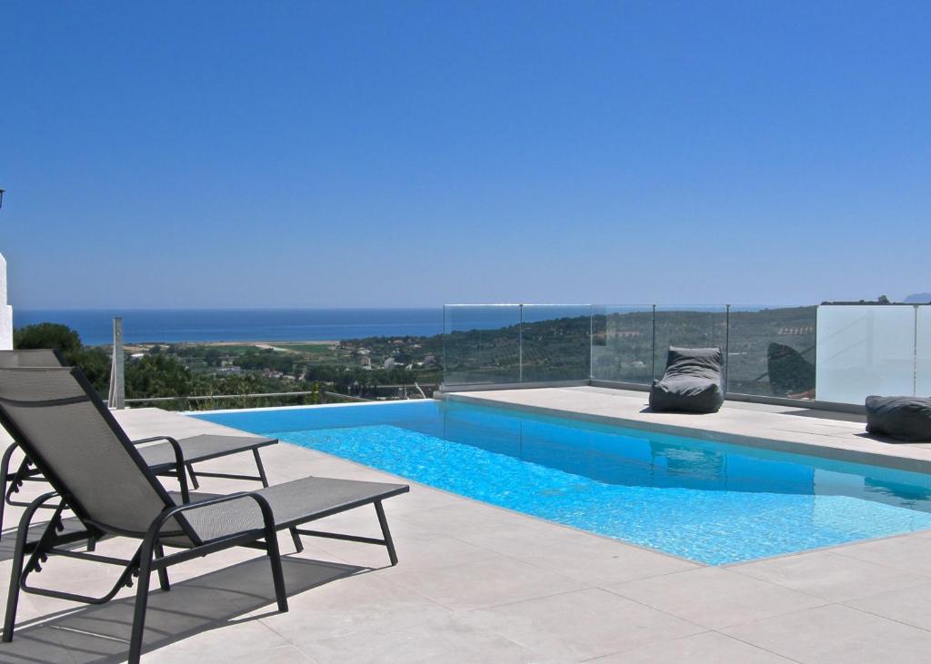 a swimming pool with two chairs and a view of the ocean at Modern villa with infinity pool close to the sea in Tavronitis