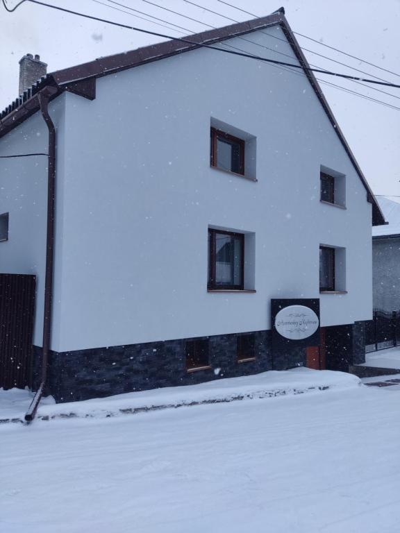 a white building with snow on the side of it at Apartmány Rejdovian in Telgárt